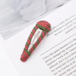Close-up of handmade pink and green striped crochet hair clip on white magazine