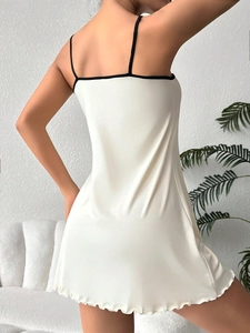 Detailed back view of creamy white slip nightdress with ruffle hem and thin black straps