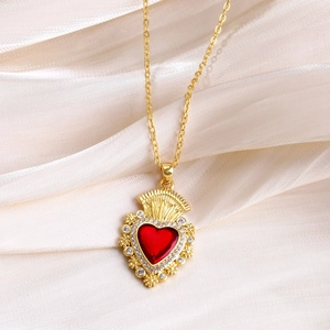 Close-up of vintage gold necklace with red heart pendant and cubic zirconia on silk