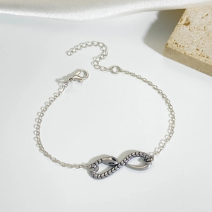 Gothic silver snake chain bracelet with infinity serpent charm on a stone background
