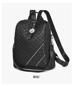 Detailansicht eines schwarzen Rucksacks mit Karomuster und Smile-Anhänger