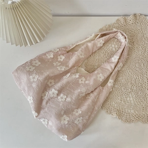 Detailed embroidery of white flowers on a soft pink cotton tote bag with wide shoulder straps