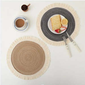 Macro shot of circular woven placemats with fringe details in dark gray and khaki colors