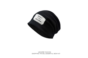 Detail of black knit beanie with white seasonal fabric patch and leisure fashion label