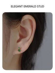 Macro shot of gold S925 earrings with emerald green stones worn by model