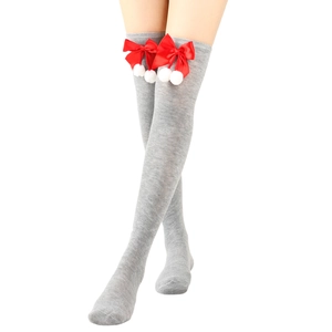 Detail of grey knitted over-knee socks featuring festive red bows and white pom-poms