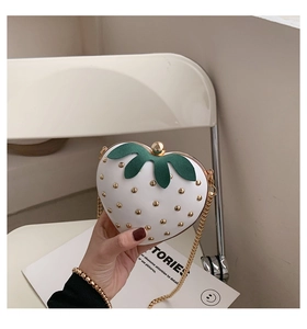 Close-up of strawberry heart bag featuring gold studs and elegant chain strap detail
