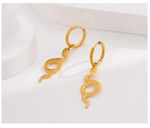 Macro detail of golden snake-shaped drop earrings with textured skin on white stand