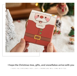 Detail of Christmas gift box with Santa Claus motif and golden rope held by hand