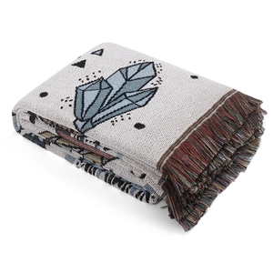 Detail of bohemian picnic blanket featuring crystal patterns and colorful woven tassels