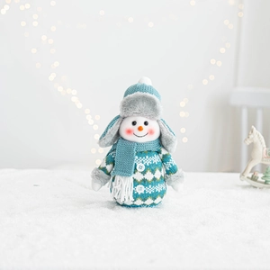 Detail of a Christmas snowman plush doll with knit blue sweater and faux snow background