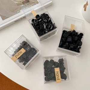 Detailed view of mini black hair claws in glossy and matte finishes within clear boxes