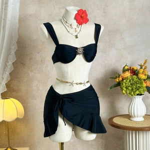 Ensemble bikini noir avec détail métallique et jupe de plage élégante à volants