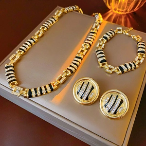 Macro shot of gold jewelry set with black enamel stripes and diamonds in a display box
