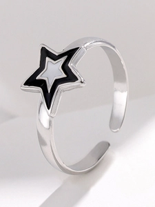 Close-up of a minimalist star-shaped open ring with black and white enamel finish
