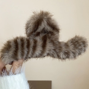 Close-up of brown striped plush hair claw clip held against a white sweater