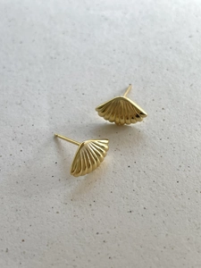 Detail of fan-shaped shell earrings in gold metal finish with textured radial ribs