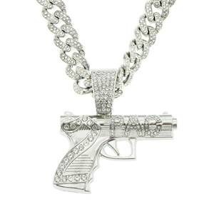 Détail du pendentif pistolet argenté serti de diamants avec lettrage PAC sur chaîne