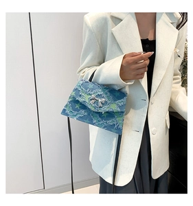 Détail du sac bandoulière en denim avec étoiles vertes et ornement nœud métallique