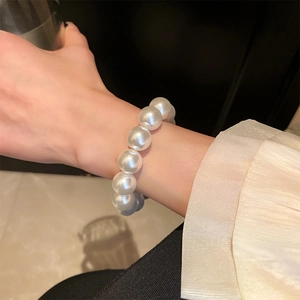 Close-up of large round white pearls on an elastic bracelet worn on a woman's wrist
