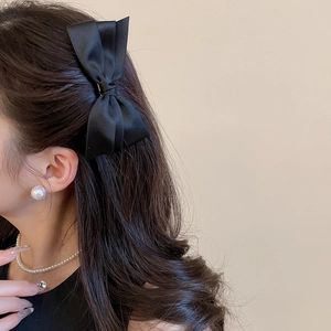 Gros plan sur l'élégante pince à cheveux nœud en satin noir avec bijoux en perles