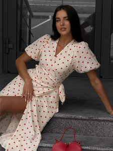 Detail of white cotton wrap dress with red heart print, puff sleeves and side split