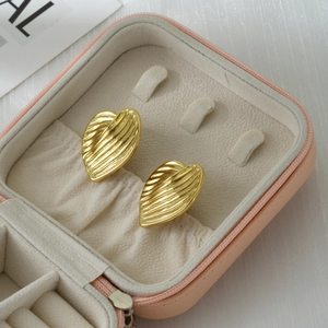 Detail of gold heart earrings with textured leaf veins in a pink velvet jewelry box
