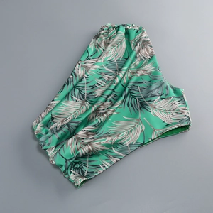 Macro detail of green palm leaf print on premium glossy silk satin fabric texture