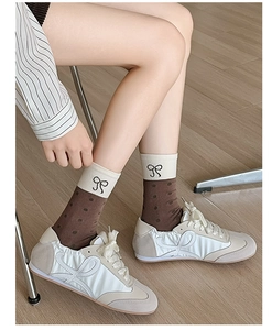 Detail of beige and brown polka dot crew socks with bow embroidery on female model