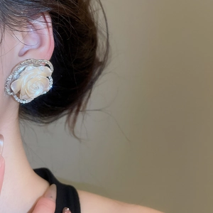 Close-up of white resin flower earring with silver diamond frame on a model