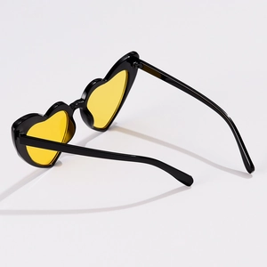Detail of heart-shaped sunglasses with black frames and vibrant yellow transparent lenses
