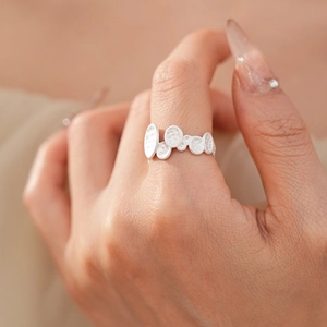 Detail of silver textured disc ring on finger showing hammered metal craftmanship