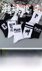 Close-up of crew socks featuring embroidered letters and cat motifs in black and white