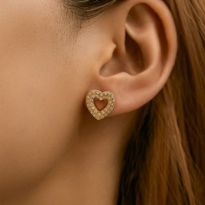 Close-up of model wearing gold heart stud earrings with sparkling pave-set cubic zirconia
