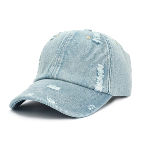 Détail de la casquette en jean délavé montrant des déchirures usées et du coton vintage