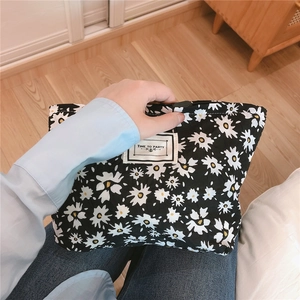 Close-up of black quilted daisy pouch with a Time to Party label held by a hand