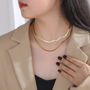 Double layered gold snake and box chain necklace worn by a model in casual chic style