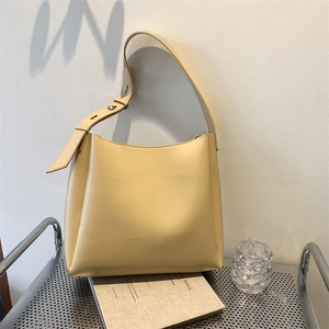 Minimalist light yellow bucket bag standing on metal table in a modern lifestyle setting