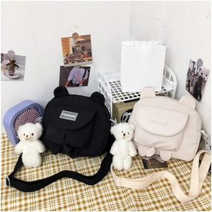 Close-up of cute canvas crossbody bags with animal ear details and plush bear charms