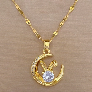 Detailed view of a gold moon and rabbit necklace with small diamonds and a large clear gem