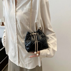 Quilted black bucket bag with gold chain and pearl drawstring on fashion model