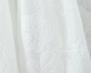 Vue macro des broderies florales blanches sur tissu élégant pour haut et jupe
