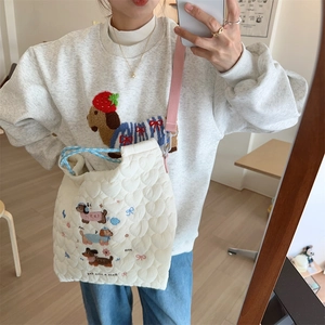 Detail of cream quilted tote bag with cute puppy embroidery and pink shoulder strap