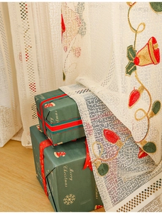 Detail of Christmas white lace curtain with embroidered bells and festive light strings