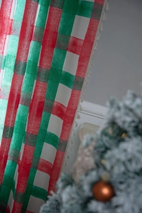 Detail of red and green plaid curtain with beige tassel trim for Christmas decor