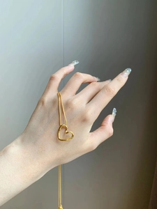 Detail of twisted open heart pendant necklace in gold finish worn by model