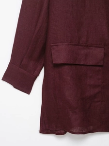 Detailed texture of burgundy linen blazer showing sleeve cuff and flap pocket detail