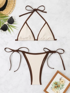Flat lay of cream textured triangle bikini set with dark brown ties on marble surface