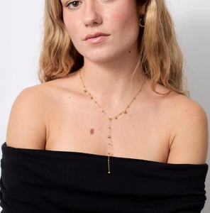 Gros plan d'un collier en Y plaqué or 18 carats avec perles et pompon style minimaliste