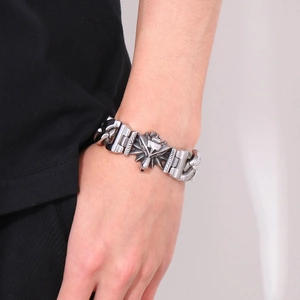 Detail of vintage wolf head charm on wide stainless steel chain bracelet for men